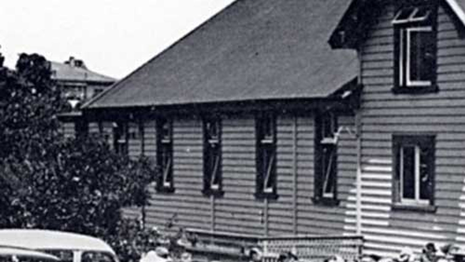 The original weatherboard church hall, photographed in the early 1900s with a crowd gathered outside.